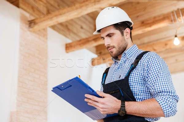 7104767_stock-photo-happy-builder-writing-notes-in-hardhat-with-clipboard